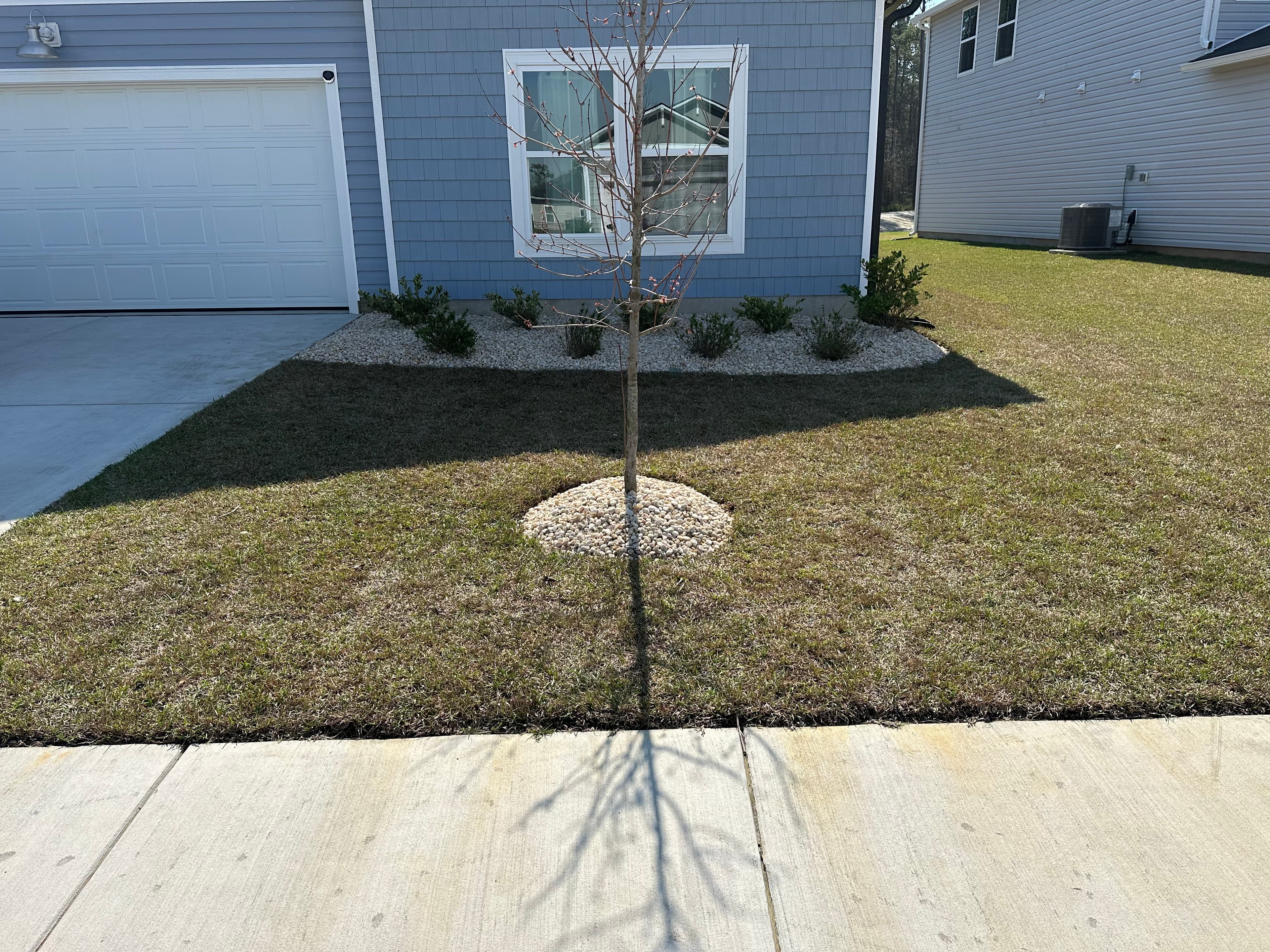 Defined stone beds and borders framing a front lawn